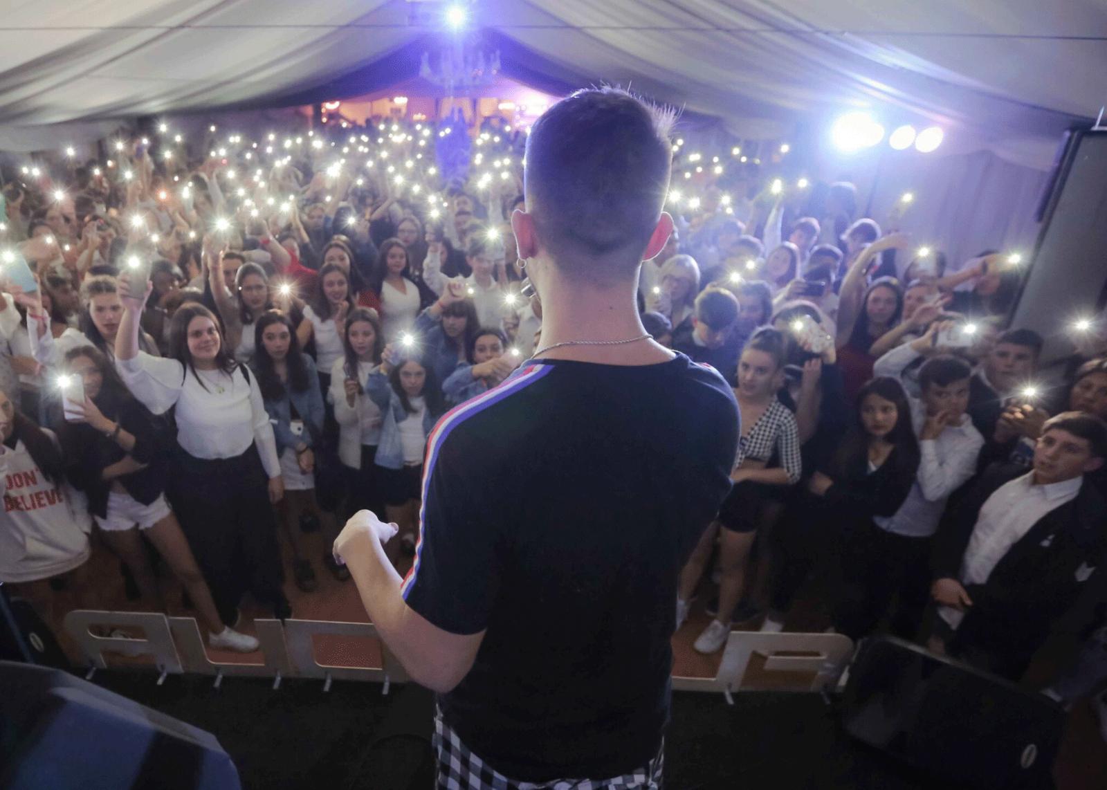 Público de un evento de egresados con luces de celulares